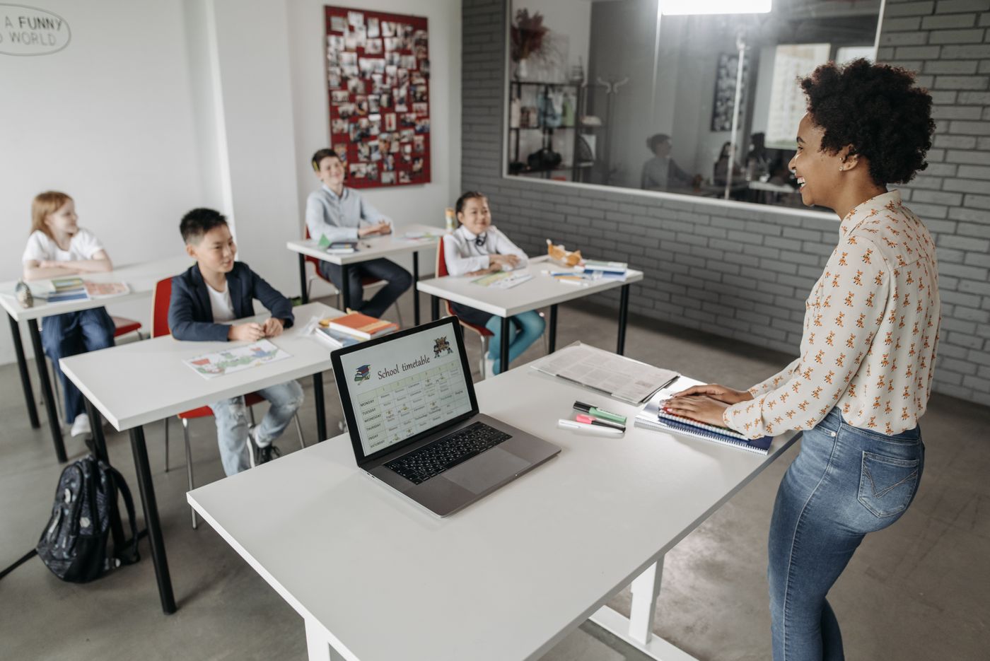 A teacher at the front of a classroom with a laptop
