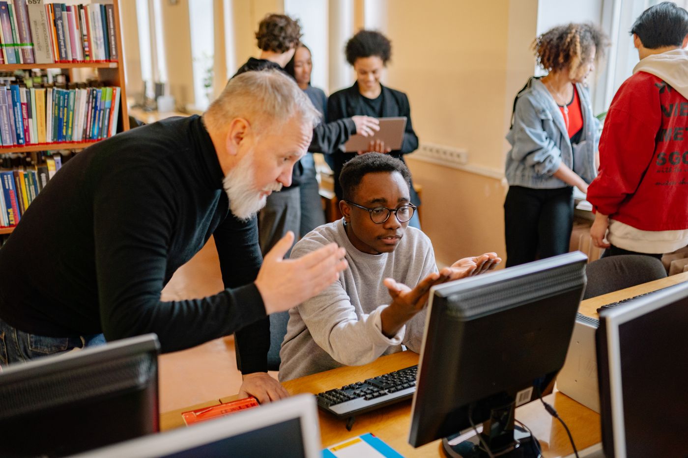 A teacher helping a student at a computer