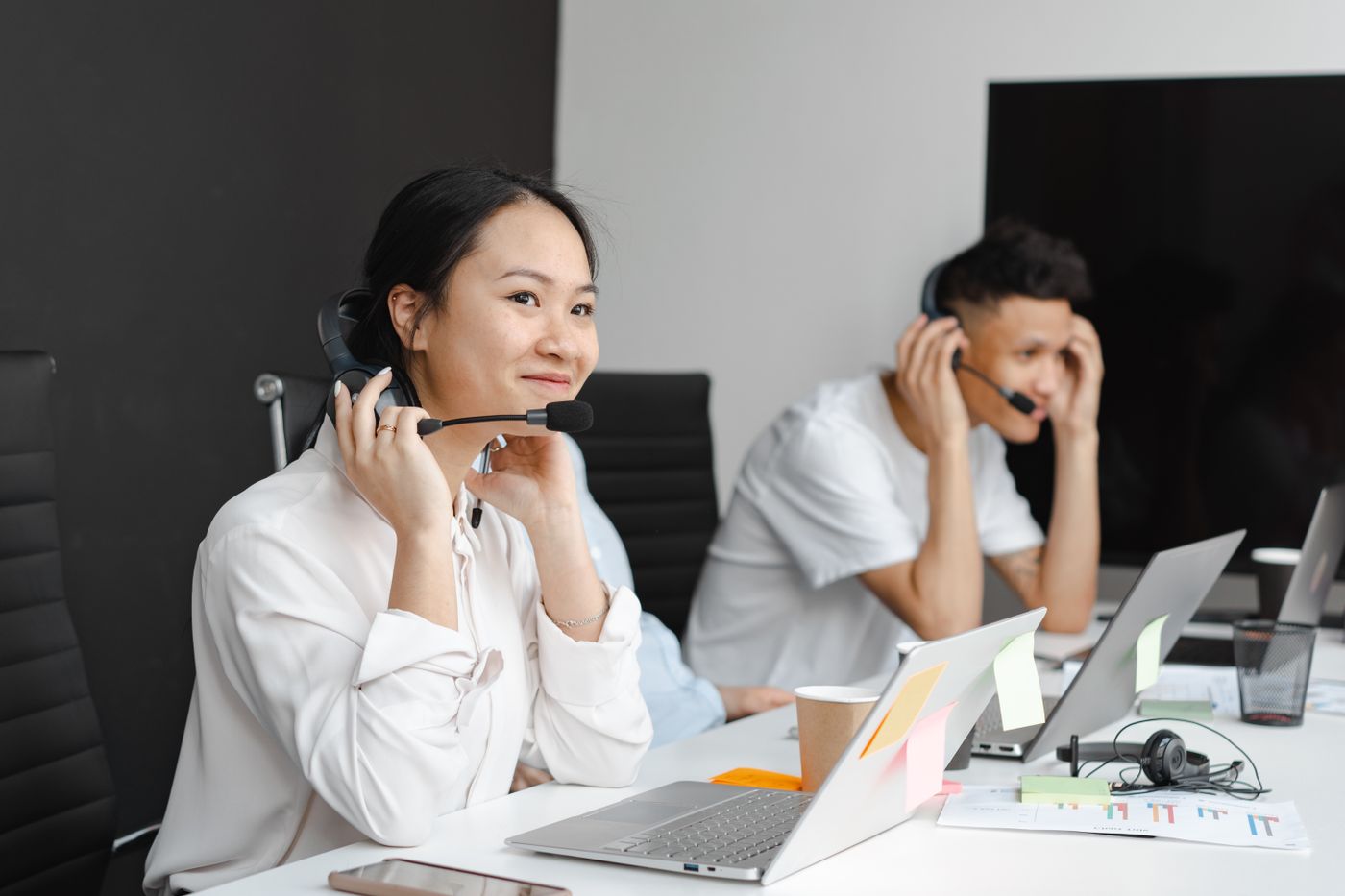 Two people talking through headsets at their laptops